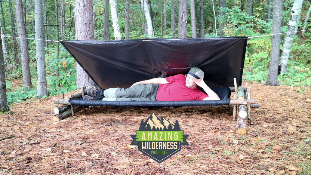 Man lying on cot under rain poncho