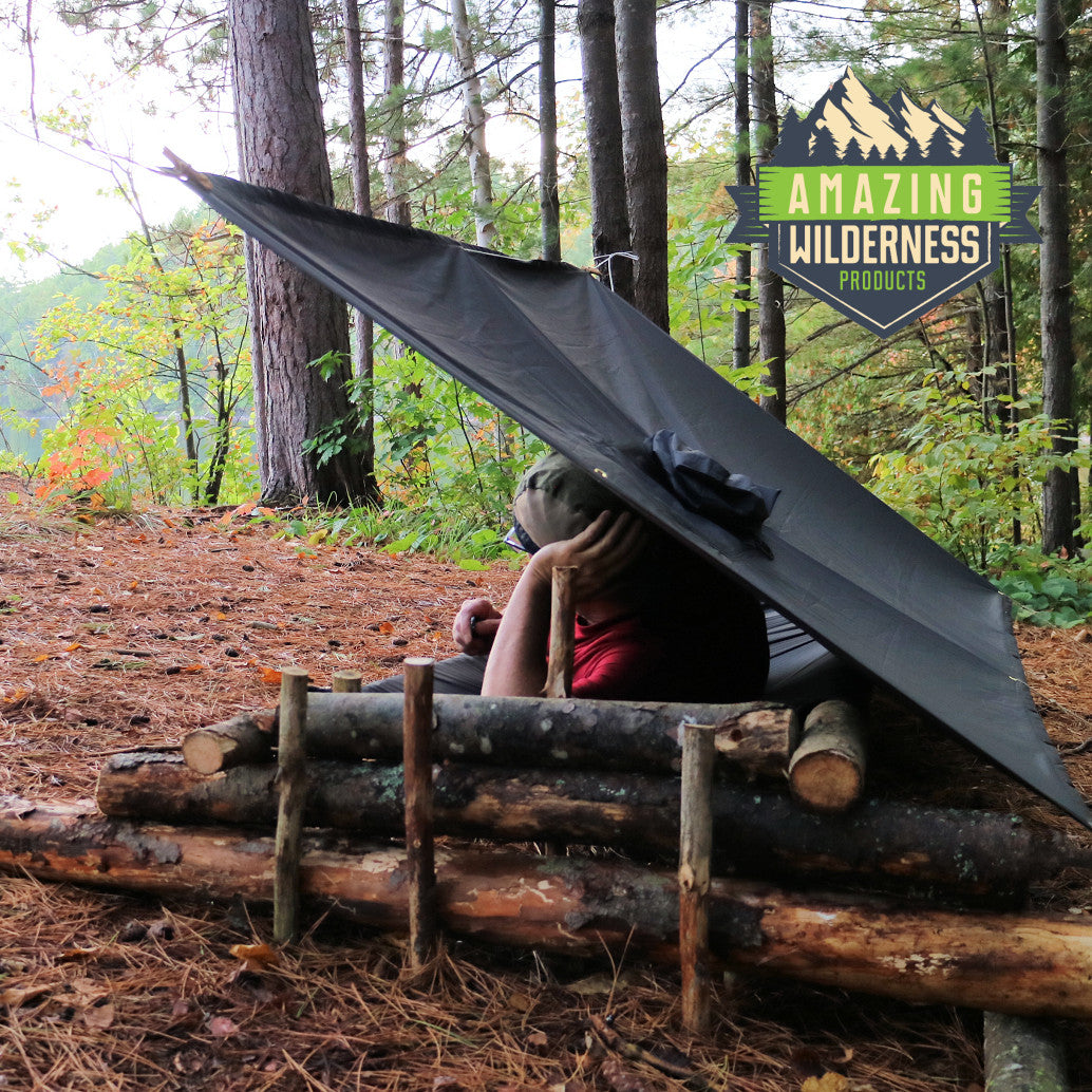 Man lying on cot under rain poncho