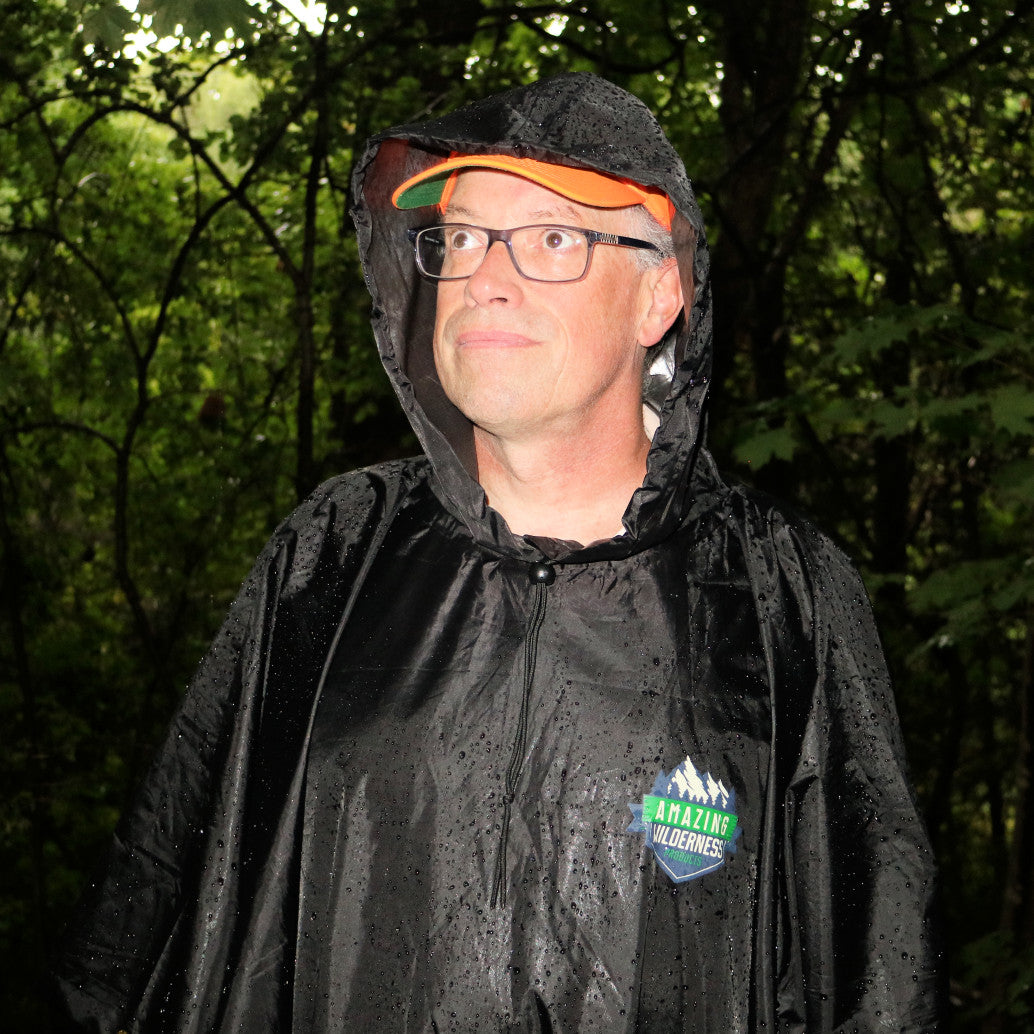 Man wearing rain poncho and ball cap